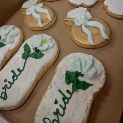 Iced sugar cookies for a bridal shower, with white flowers and the word bride in green script