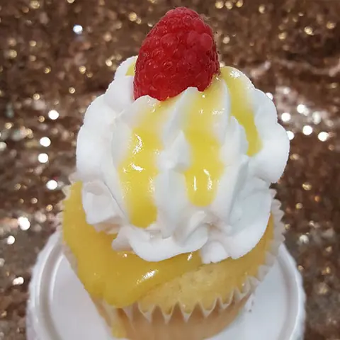 A lemon cupcake with a raspberry on top