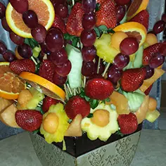 A tall fruit bouquet with orange slices and grape skewers