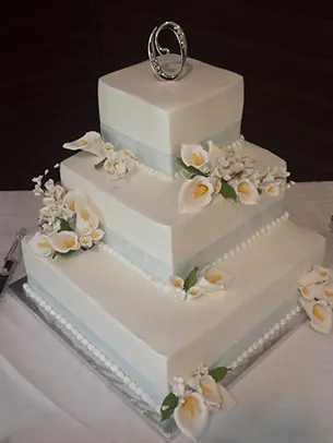 A square tiered cake with white sugar flowers